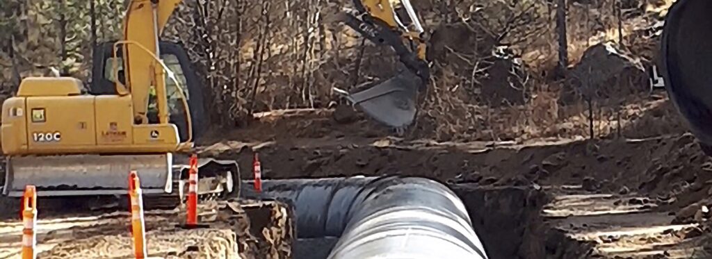 Irrigation pipe installation with an excavator in Oregon.