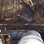 Irrigation pipe installation with an excavator in Oregon.