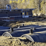 Installed Weholite water detention system installed beside a building in a forest.