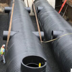 Three large Weholite pipes installed in an underground opening lined with metal walls.