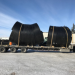 Weholite pipe strapped down on a flatbed trailer for transportation.