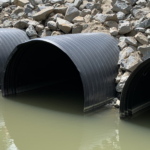 Trois conduites Weholite installées sous une route pour le passage de l'eau.